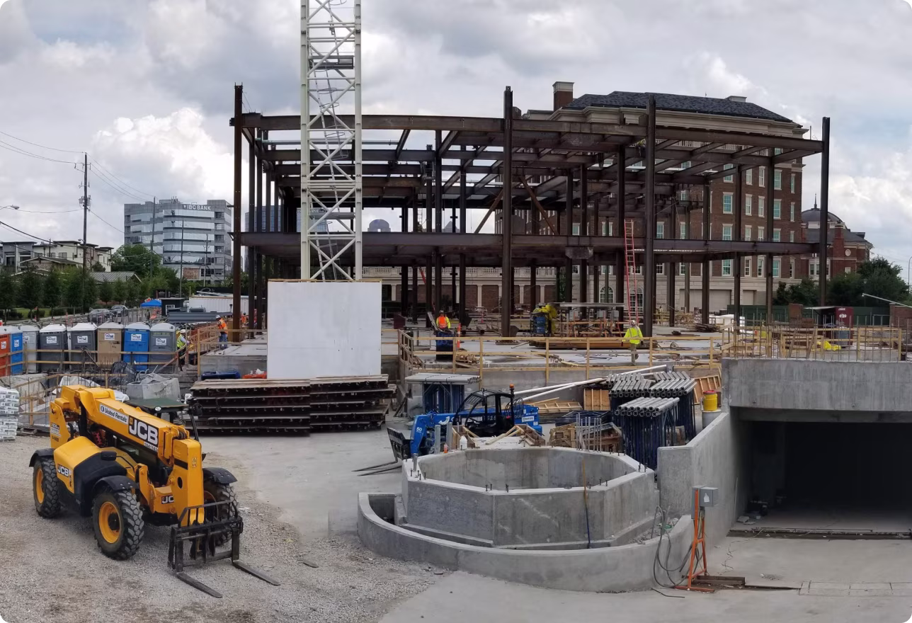 Active commercial construction site with steel structure and heavy equipment managed with inTakt